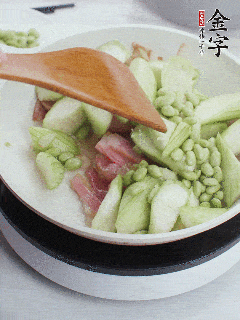 依次下絲瓜、青豆翻炒，炒至絲瓜打蔫縮小。
